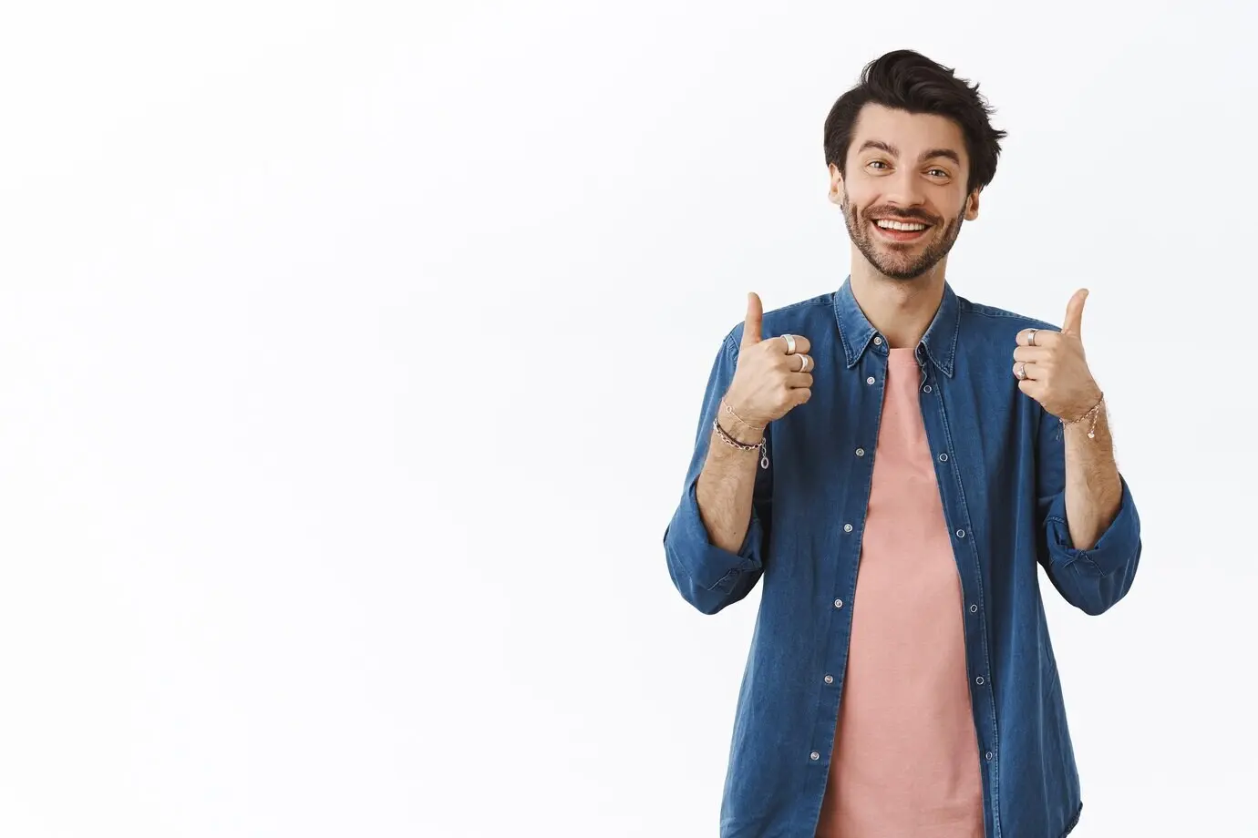 Довольный, дружелюбный, привлекательный белый мужчина в повседневной одежде показывает большой палец вверх, оценивая что-то как хорошее, улыбается и кивает в знак согласия, оставляет позитивный отзыв, считая, что это превосходно.